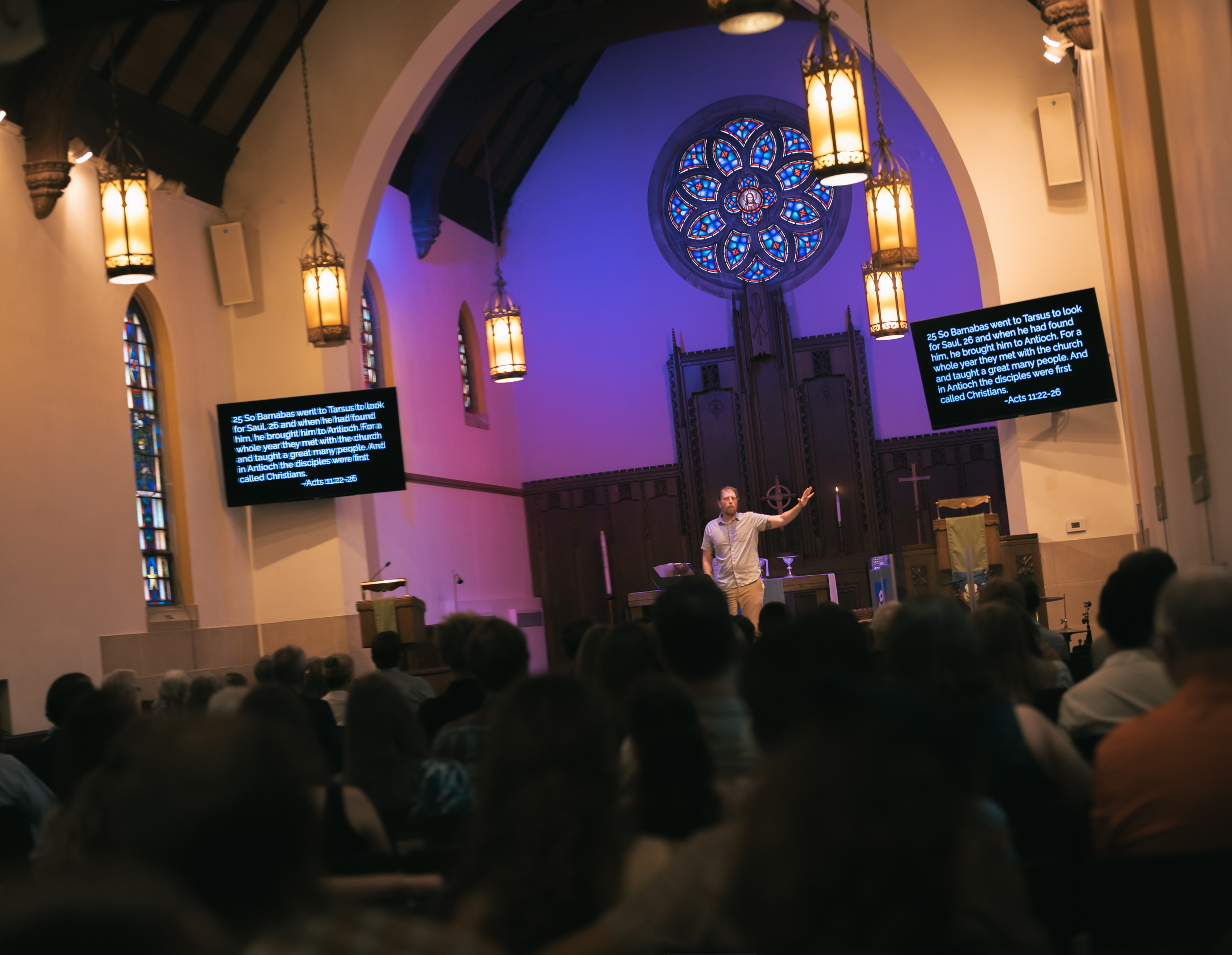Pastor preaching in the sanctuary with the rose window